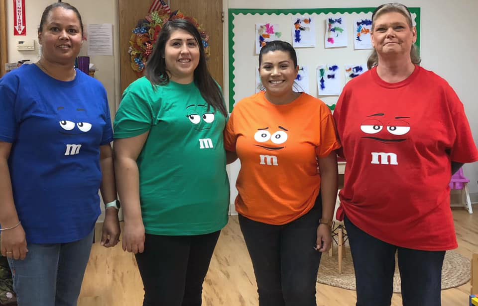 Teachers smiling wearing M&M's shirt in different colors at A Preschool & daycare Serving Armona, CA